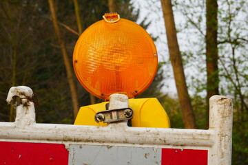 yellow construction site warning lamp attached to a red and white barricade