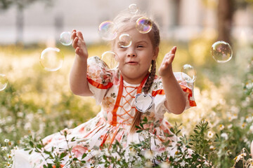 A girl with Down syndrome blows bubbles. The daily life of a child with disabilities. Chromosomal...