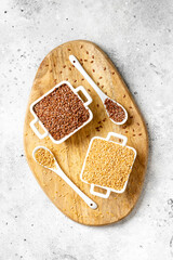 Brown and white golden flax seeds in white bowls on a light gray background. Healthy vegetarian food