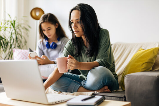 Single mother working from home with preteen daughter around