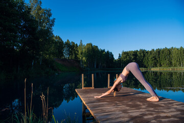 Fototapeta na wymiar Beautiful young woman performing a spiritual yoga pose on a forest lake at sunny day, sunrise zen wellness