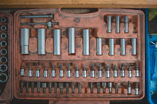 From above of old box with screwdriver and various nozzles and wrenches for auto maintenance and repair service on wooden table