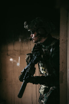 Soldier in full US MARSOC armed with assault rifle run through the abandoned building. Military clash.