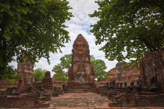 Scenery of authentic oriental Wat Phra Mahathat temple with stone Buddha statues amidst lush verdant trees in Thailand