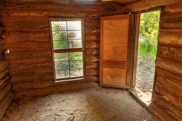 A room with a window and an exterior door in an old abandoned log cabin with a dirt floor, Josie Bassett Morris log cabin, Dinosaur National Monument, Utah