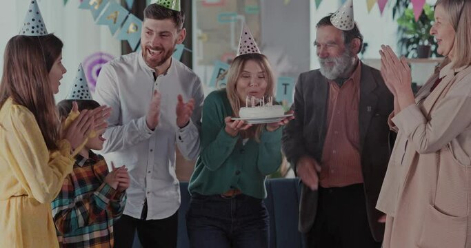 Happy multi-generation family of four members celebrating birthday party with candle cake blowing and enjoying reunion holiday.