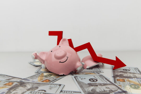Broken piggy bank and red arrow down with dollar banknotes isolated on white. Investment and bankruptcy concept