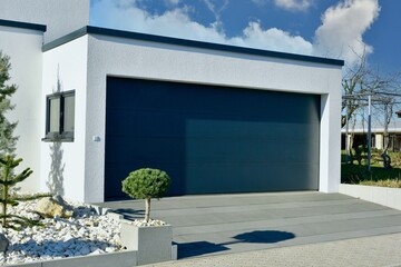 Moderne Beton-Garage mit Automatik-Tor in der Wohngebäude-Zufahrt - obrazy, fototapety, plakaty