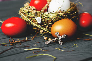 colored deep red Easter eggs in nest with cross rosary  top view background, selective focus image. Happy Easter card	
