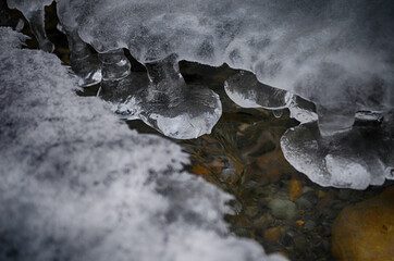 Ice-free little river in winter. Stream of river water. The snow cover. Winter abstract background.