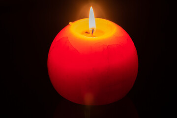 Big spherical candle shines in the dark.