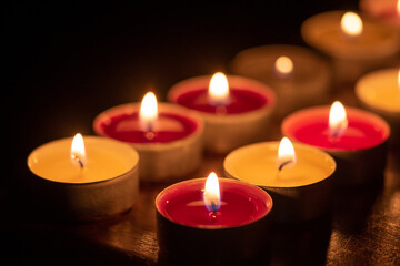 Fototapeta na wymiar background with tea light candles shines in the dark.