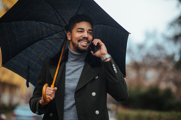 Young businessman using smart phone under umbrella in the rain © bernardbodo
