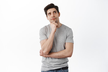 Portrait of handsome man in deep thoughts looking aside, touching chin and thinking, looking aside,...