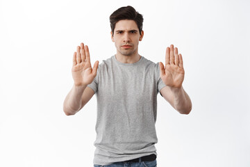 Stop it, keep distance. Serious frowning man showing block refusal gesture, stretch out hands to...