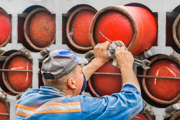Adult male worker pushing a gas cylinder into a gas machine
