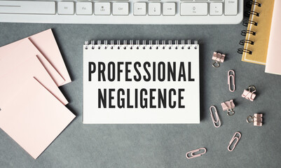 The text Professional negligence is written on a notepad and a white background, felt-tip pens and...