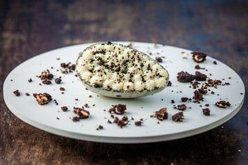 Stuffed white chocolate easter egg with broken cookies around on a white board on a wooden table. Gourmet.