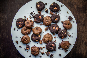 Dark and brown chocolate cookies on a white board with scattered cookies around. Gourmet. Top view.