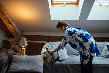 Japanese woman arranging pillows on sofa in the living room