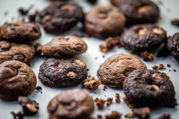 Dark and brown chocolate cookies on a white board with scattered cookies around. Gourmet. Close up.