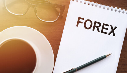 FOREX - text on paper with cup of coffee and glasses on wooden background in sinlight.