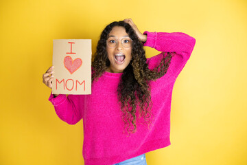 Beautiful woman celebrating mothers day holding poster love mom message very happy and excited making winner gesture with raised arms, smiling and screaming for success.