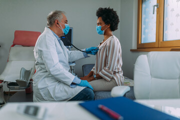 Obraz premium Senior doctor and his patient with face masks during examining at hospital