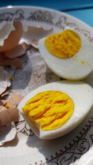 Closeup yellow yolk of hard boiled egg sliced in halves and broken eggshell on retro crockery plate. Organic farm chicken egg cooked for breakfast. Healthy eating nutrition