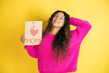 Beautiful woman celebrating mothers day holding poster love mom message relaxing and stretching, arms and hands behind head and neck smiling happy