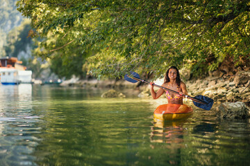 Lady paddling the kayak at the calm lake