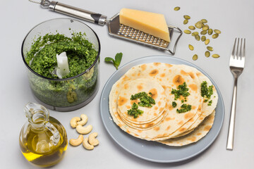 Flatbread on ceramic plate. Grinded greens in blender.