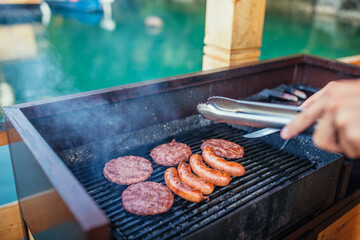 Male preparing barbecue near lake on a sunny day