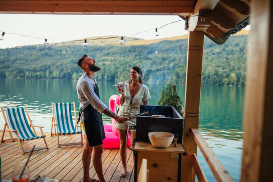 Young couple preparing a meal at the wooden pier near lake