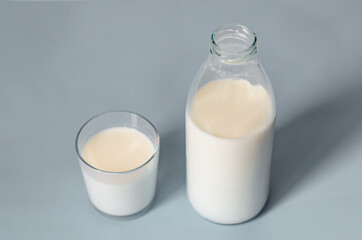 A bottle of milk or kefir and a glass nearby on a gray background. A healthy, nutritious, tasty product. Close-up copy space