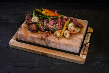 New York Delmonico grilled 30oz steak with vegetables on marble salt tray