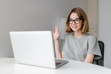 young relaxed caucasian woman smiling sitting with laptop in the apartment