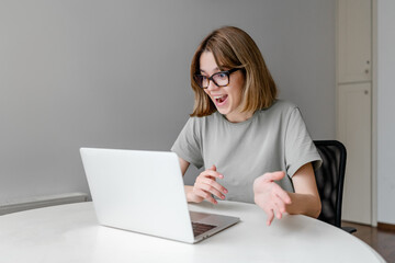 young relaxed caucasian woman speaking sitting with laptop in the apartment