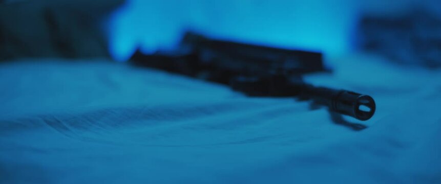 Close up of M16 rifle lying on a bed. Military, PTSD soldier concept. Cinematic handheld shot.