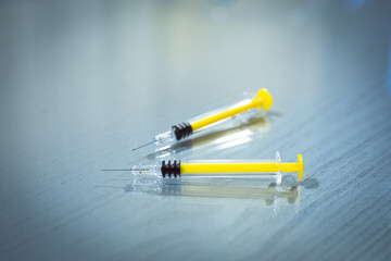 yellow syringes and needles over blue background and reflections