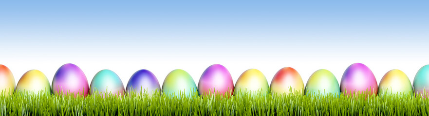 Bunte Ostereier in Frühlingswiese mit blauem Himmel Hintergrund - Panorama Banner