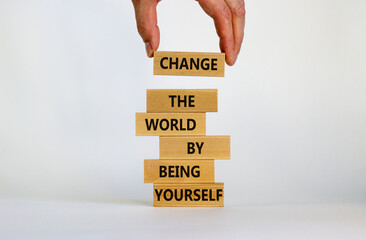 Change the world by being yourself symbol. Wooden blocks with words 'Change the world by being yourself'. Businessman hand. Beautiful white background. Business, popular quotation concept. Copy space.