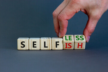 Selfish or selfless symbol. Businessman turns cubes and changes the word 'selfish' to 'selfless'. Beautiful grey background, copy space. Business, psuchological and selfish or selfless concept.