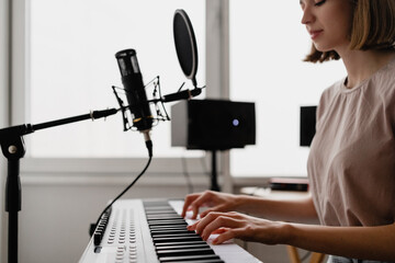 young woman recording a song playing piano and singing at home