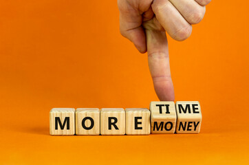 More time or money. Businessman turns wooden cubes and changes words 'more money' to 'more time' or vice versa. Beautiful orange background, copy space. Business, more time or money concept.