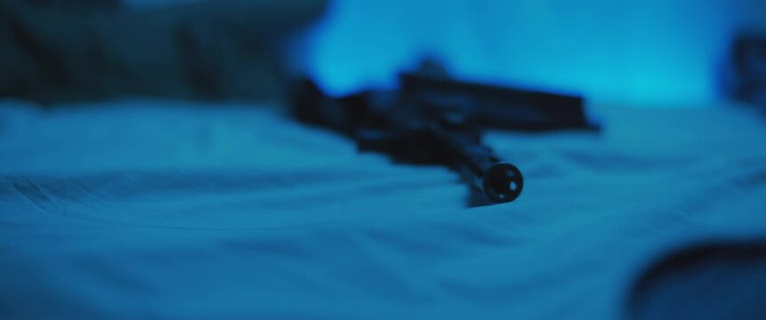 Close up of M16 rifle lying on a bed. Military, PTSD soldier concept. Cinematic handheld shot.