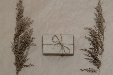 gift in craft paper on and dry grass on brown background