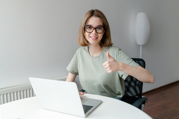 Happy Smiling Girl Working Online Or Studying And Learning While Using Notebook showing thumb up. Freelance Work Concept