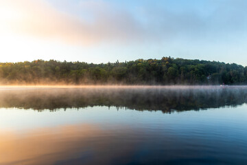 symétrie d'un paysage avec brume matinale sur le lac au matin lors d'un lever de soleil enflammé