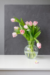 pink tulips with green leaves in a glass vase, a woman holding tulips in her hands, florist, floristry, mother's day gift, bouquet for March 8, bouquet for a girl on her birthday, bouquet of tulips